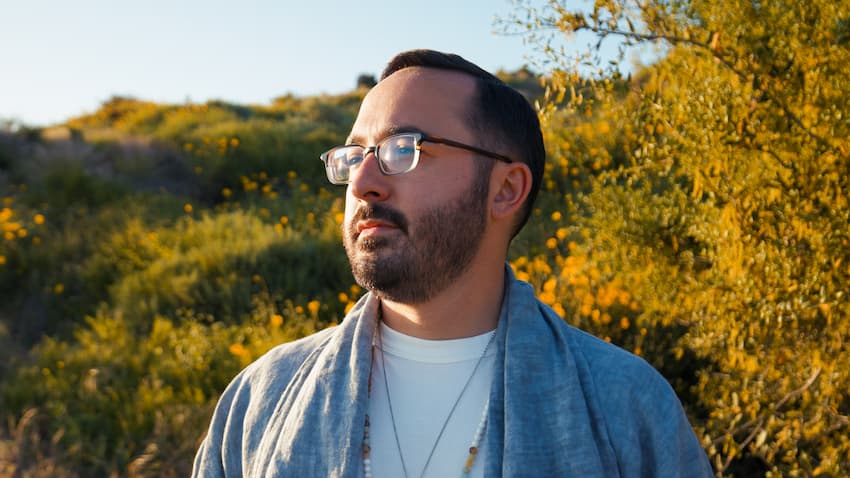 Dr. Cameron Martin standing outdoors among wildflowers